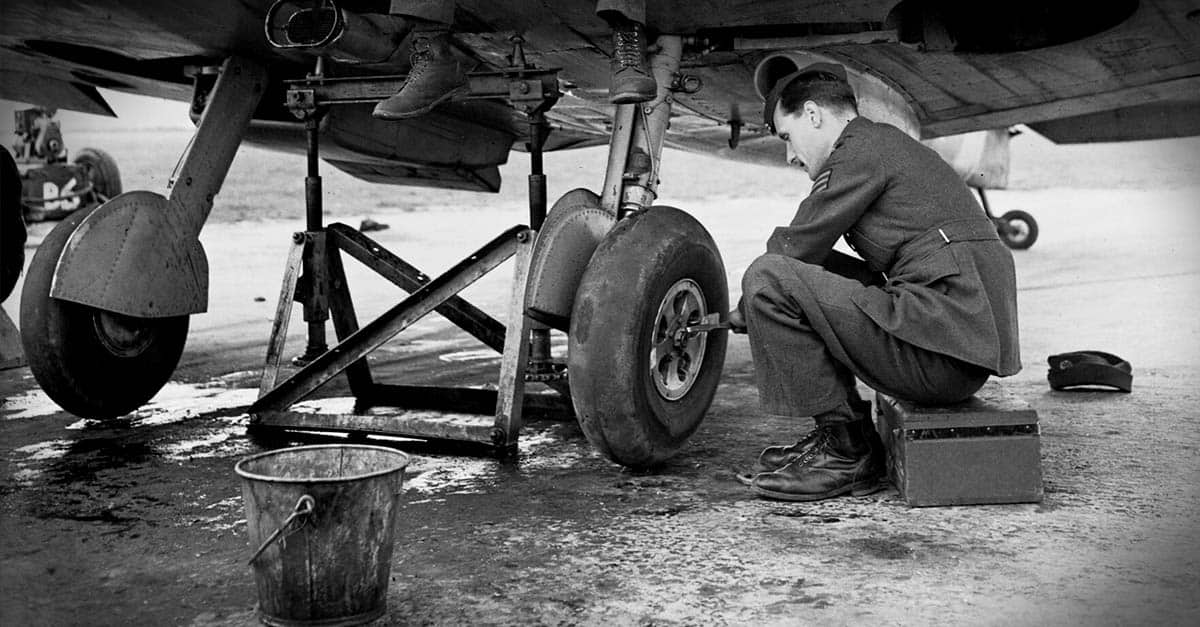 Supermarine Spitfire- Ground staff worker looks at wheel on a No. 610 Squadron Spitfire Mk V