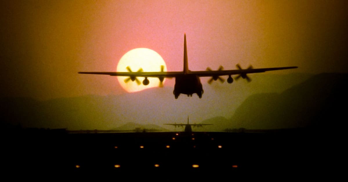C-130_Silhouetted by the setting sun, a C-130 Hercules aircraft prepares to land during a 10-ship air drop exercise